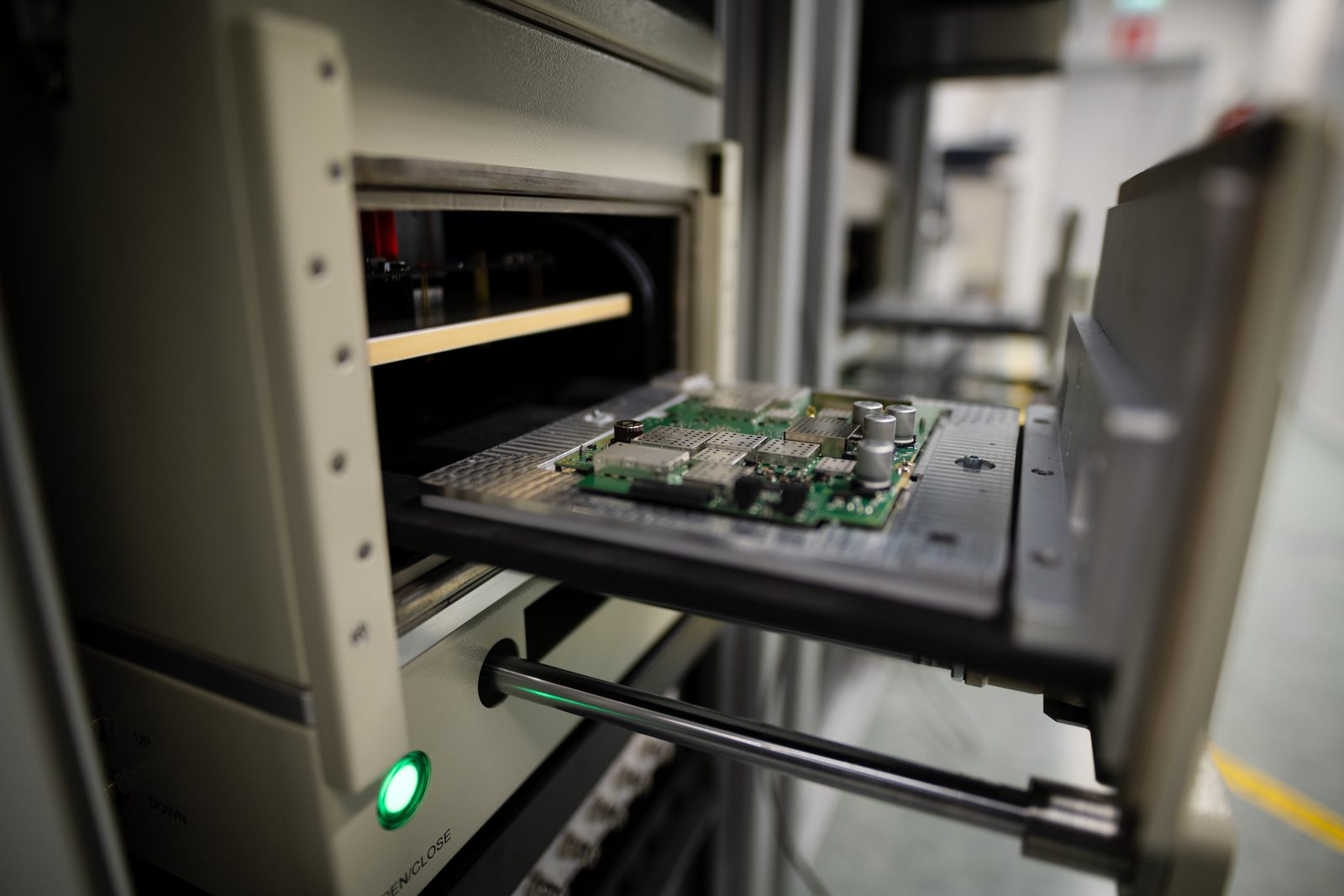 Circuit board on a test fixture tray sliding out of a production tester